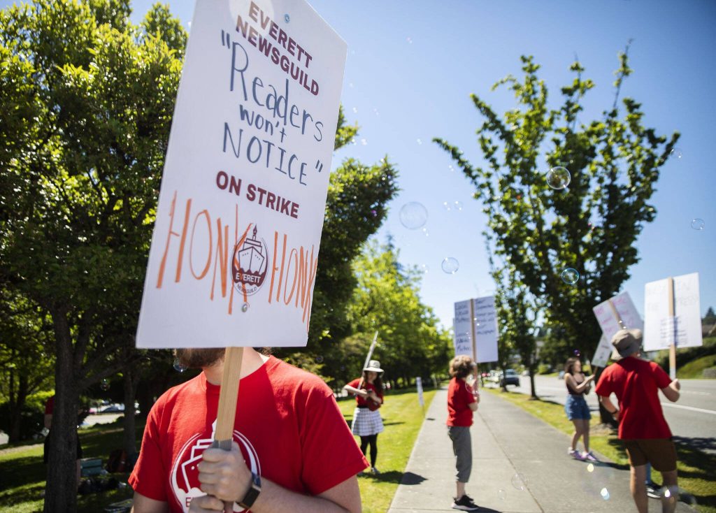 Jordan Hansen holds a sign that displays a quote by Vice President and Publisher of the Daily Herald Rudi Alcott during the second day of the Everett NewsGuilds strike on Tuesday, June 25, 2024 in Everett, Washington. (Olivia Vanni / The Herald)