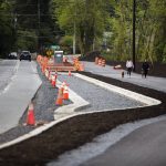 Traffic moves along Filbert Drive next to pedestrians walking along a new section of the North Creek Regional Trail on Friday, April 29, 2022 in Bothell, Washington. (Olivia Vanni / The Herald)