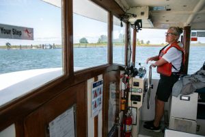 Captain Kristi Schooley navigates the Jetty Island ferry to the dock at while toting passengers to and fro on Friday, July 7, 2023, in Everett, Washington. (Ryan Berry / The Herald)