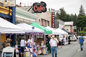 People walk along Olympic Avenue past Lifeway Cafe and Olympic Theater that currently hosts Lifeway Church on Friday, July 7, 2023 in Arlington, Washington. (Olivia Vanni / The Herald)