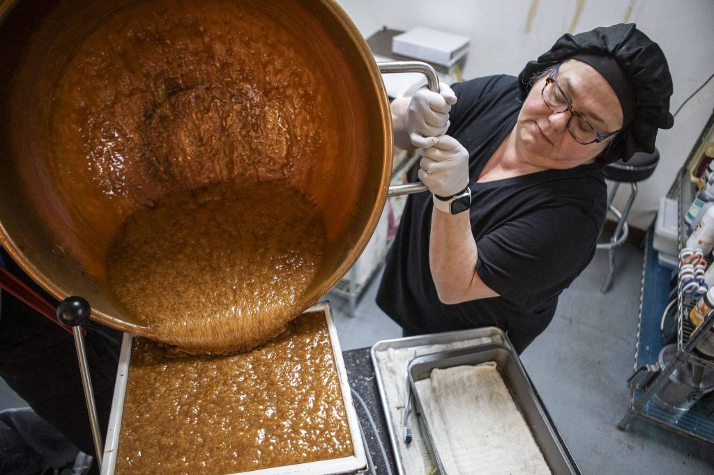 Mona Newbauer pours caramel into a machine inside her store Sweet Monas Chocolates on March 21, 2024 in Langley. (Annie Barker / The Herald)