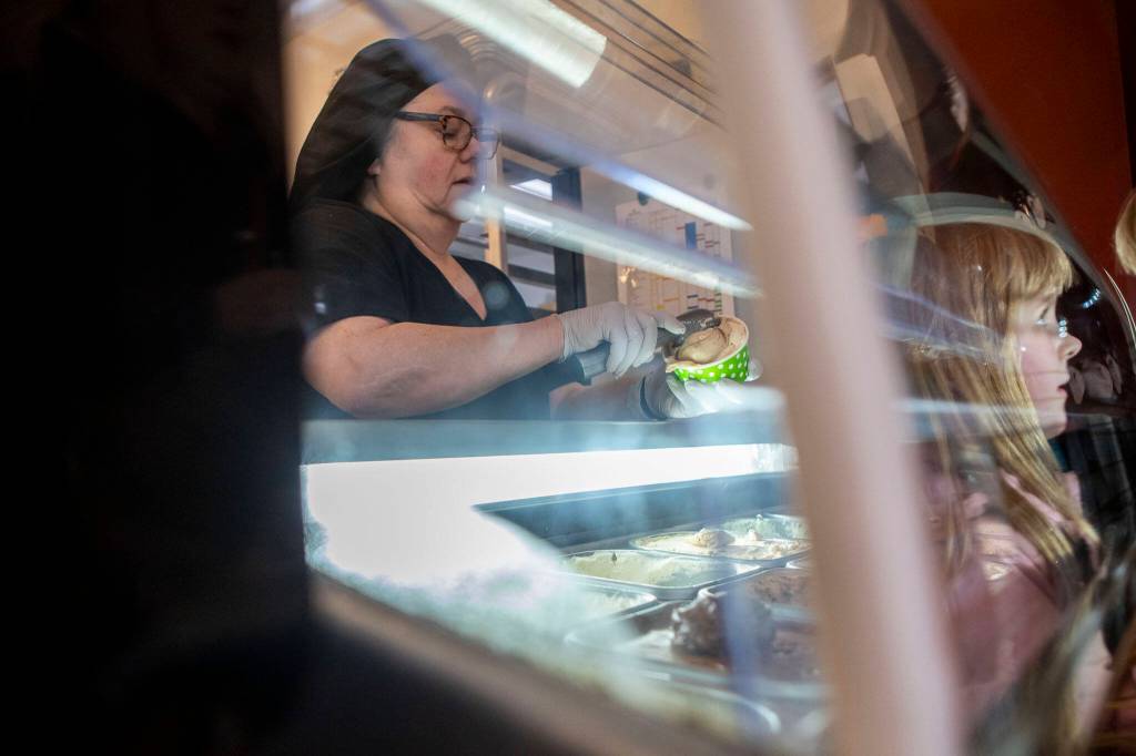 Mona Newbauer scoops gelato while a child watches inside her store Sweet Monas Chocolates. (Annie Barker / The Herald)