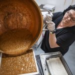Mona Newbauer, 62, pours caramel into a machine inside her store Sweet Mona's Chocolates on March 21, 2024 in Langley, Washington. (Annie Barker / The Herald)