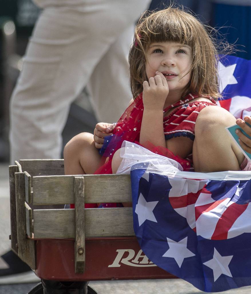 A child rides in a wagon during the Fourth of July parade in downtown Everett, Washington, on Tuesday, July 4, 2023. (Annie Barker / The Herald)