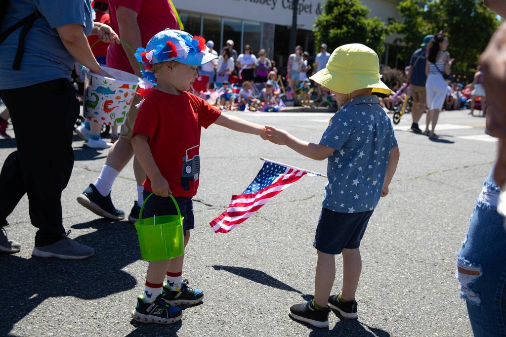 Two children exchange candy during Everetts Fourth of July Parade on Thursday, July 4, 2024, in downtown Everett, Washington. (Ryan Berry / The Herald)