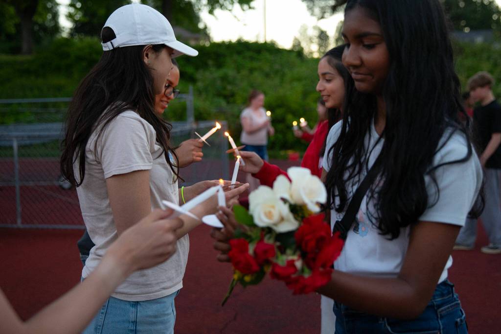 People begin sharing flames to light candles at the conclusion of a vigil held in memory of Jayda Woods-Johnson at Mountlake Terrace High School on Sunday, July 7, 2024, in Mountlake Terrace, Washington. (Ryan Berry / The Herald)