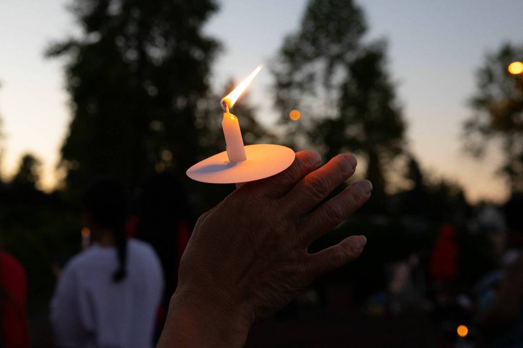 A woman raises her candle in the air during a vigil held in memory of Jayda Woods-Johnson at Mountlake Terrace High School on Sunday, July 7, 2024, in Mountlake Terrace, Washington. (Ryan Berry / The Herald)