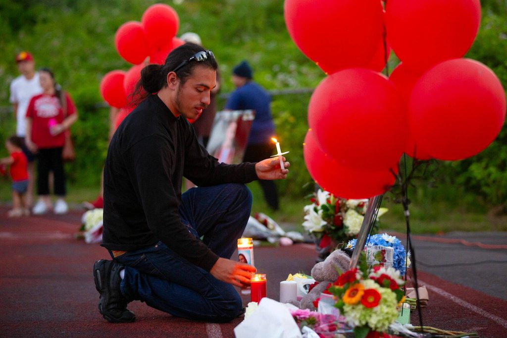 People begin leaving candles in front of a photo of Jayda Woods-Johnson during a vigil held in her memory at Mountlake Terrace High School on Sunday, July 7, 2024, in Mountlake Terrace, Washington. (Ryan Berry / The Herald)