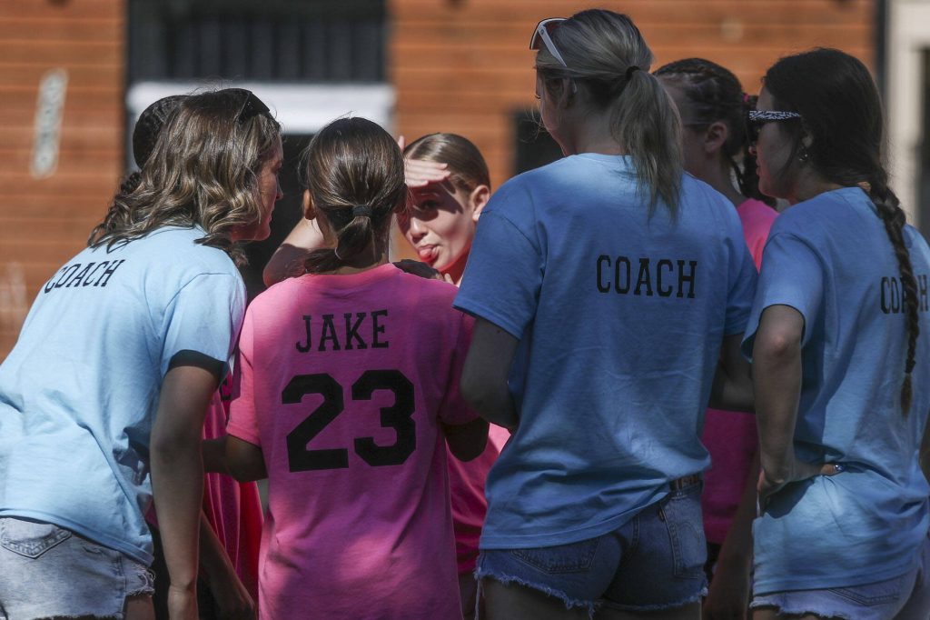 Players and coaches of We Fired The Dads huddle during the Everett 3on3 tournament in downtown Everett, Washington on Sunday, July 14, 2024. (Annie Barker / The Herald)