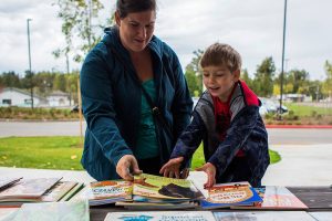 Samantha Grospe helps her son Everett Grospe, 4, pick a book during Lake Stevens Education Foundation Dolly Parton Imagination Library celebration on Sept. 21, 2018 in Lake Stevens, Wa. (Olivia Vanni / The Herald)