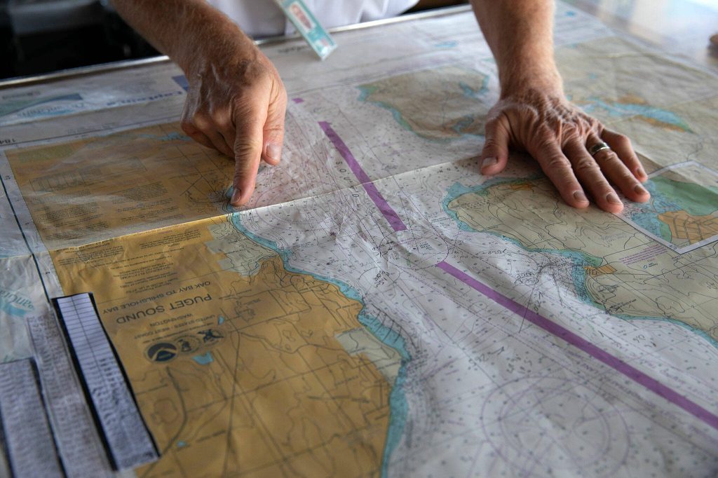 Captain Russell Fee uses a map to point out different nearby features aboard the MV Spokane on the Edmonds/Kingston ferry route Thursday, July 18, 2024, near Edmonds, Washington. The longtime practice of using paper maps will end in August, as the ferry system will have all maps digitally available to crew. (Ryan Berry / The Herald)