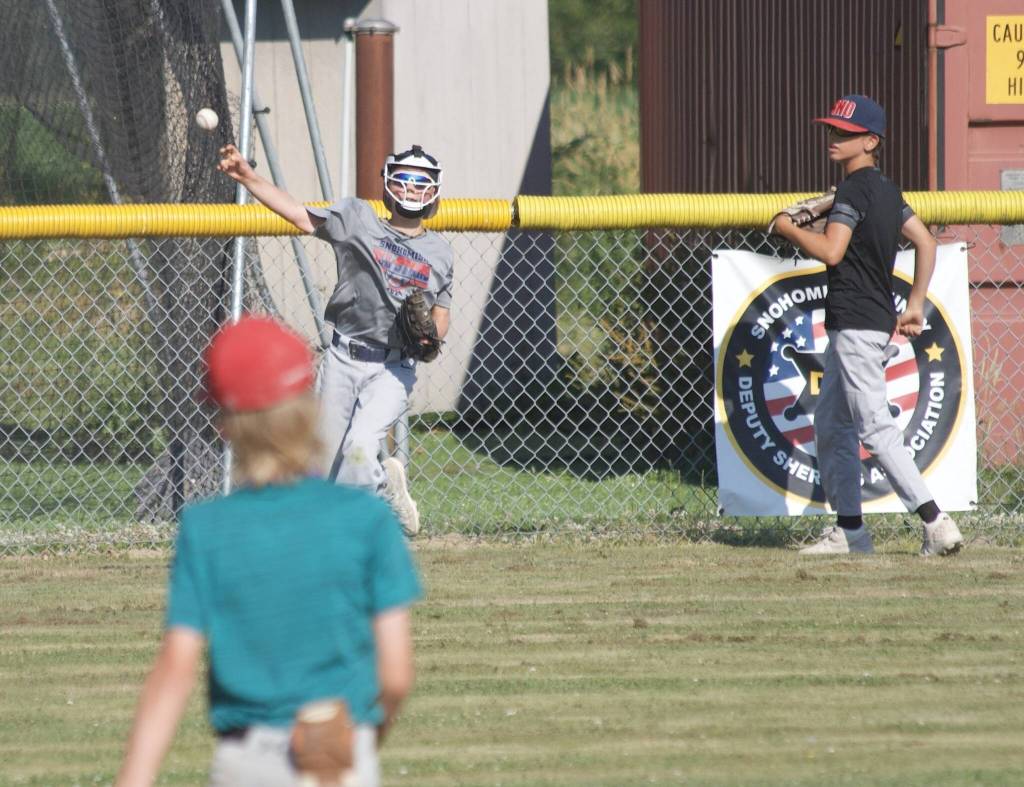 Leo Giovannetti throws the ball to Barrett Stedford with Abel Ellis (right) in the background during practice at the Snohomish Little League Complex in Snohomish, Washington on Thursday, July 18, 2024. (Taras McCurdie / The Herald)