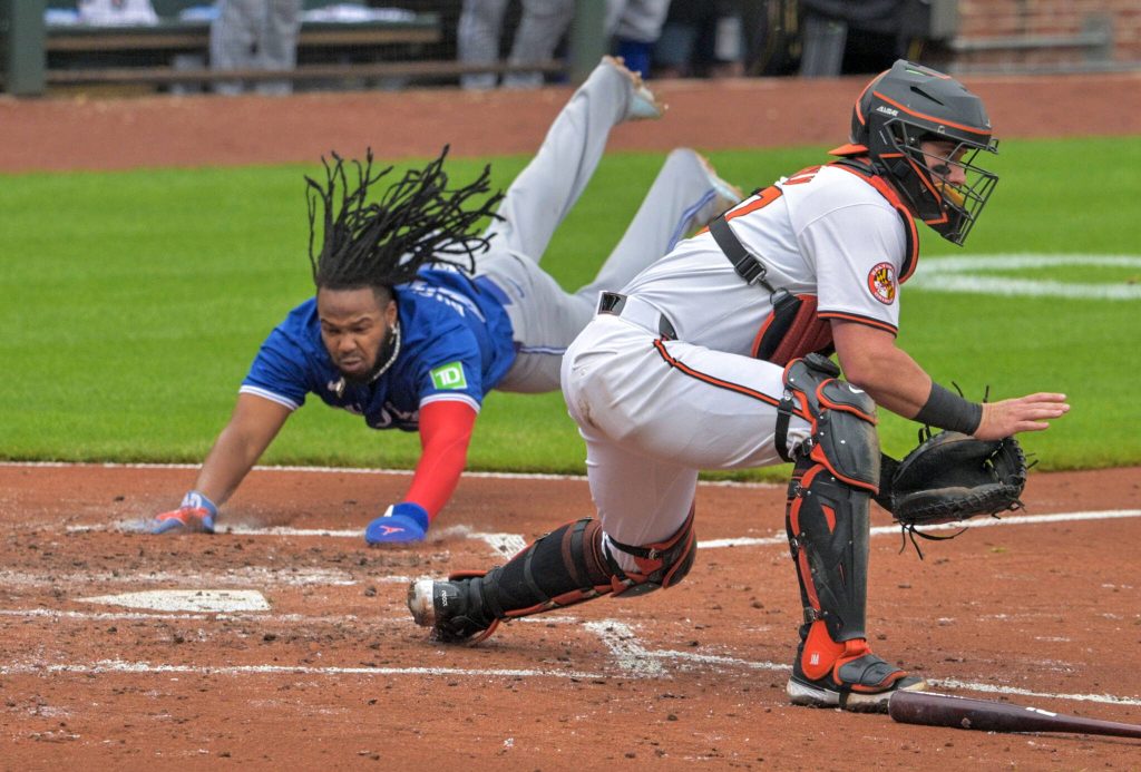 Toronto Blue Jays Vladimir Guerrero Jr. bellyflops to the plate, scoring on a drive from batter Bo Bichette as Baltimore Orioles catcher James McCann awaits a late throw during an AL-East division contest in Major League baseball at Oriole Park at Camden Yards. (Karl Merton Ferron / Baltimore Sun)