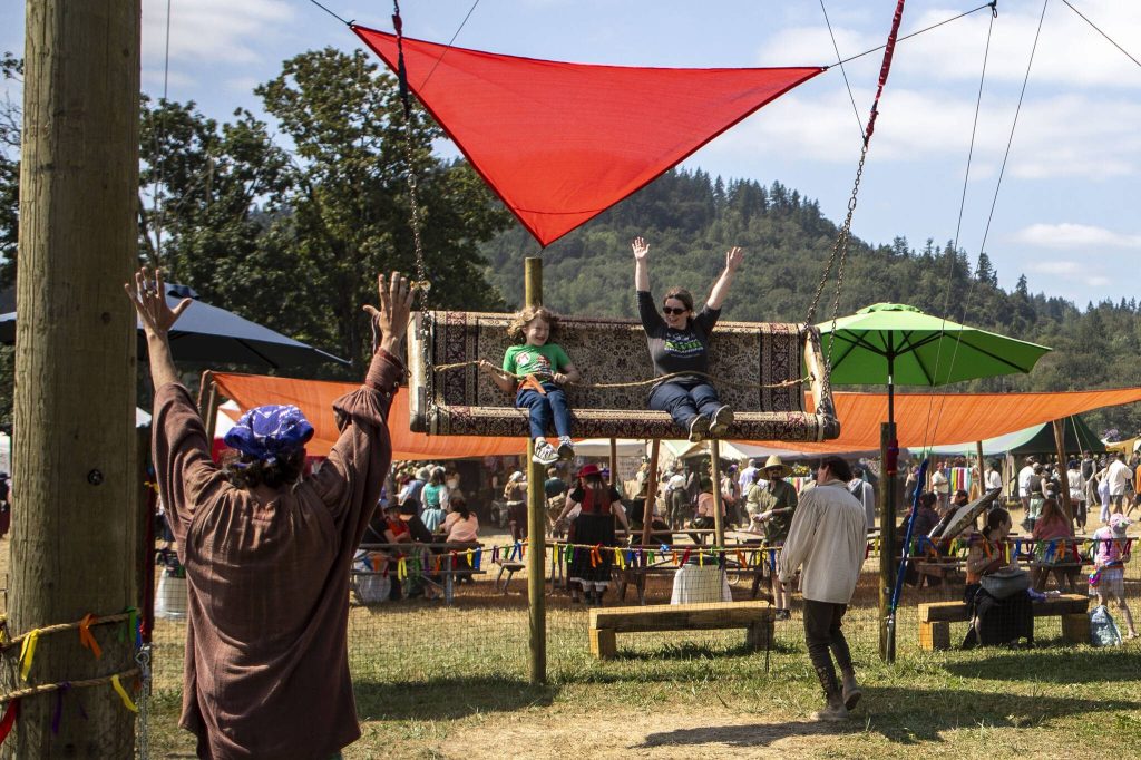 People ride a swing at the Washington Midsummer Renaissance Faire near Monroe on Sunday. (Annie Barker / The Herald)