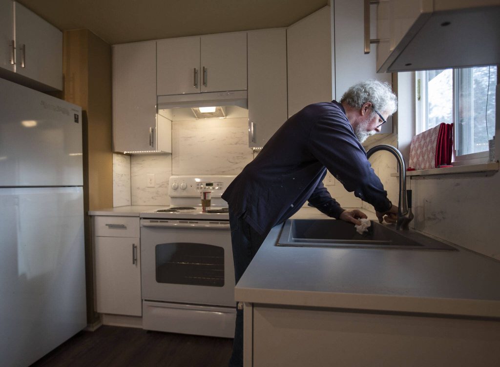 Jim Dean works on sealing the edges of a newly installed sink at the Interfaith Family Shelter on Thursday, Dec. 15, 2022 in Everett, Washington. (Olivia Vanni / The Herald)