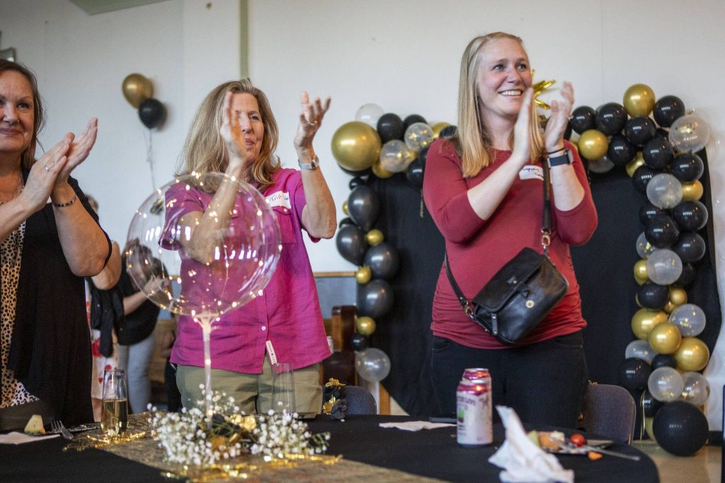 Lynsey Gagnon, right, applauds during Interfaith Family Shelter Executive Director Jim Deans retirement party at Trinity Episcopal Church in Everett, Washington, on Thursday, July 25, 2024. (Annie Barker / The Herald)