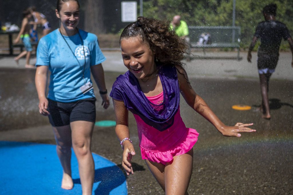 Counselor Emily Crawford, left, and Kaliya Ki Ki Plakio, 8, right, play at the water park during Camp Prov at Forest Park in Everett, Washington on Wednesday, July 24, 2024. (Annie Barker / The Herald)
