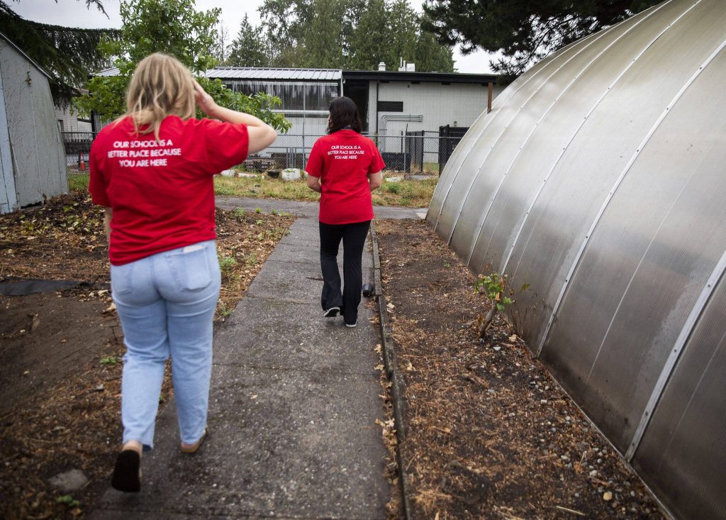 Claire Luvera, left, and Kayla Carter walks down a concrete path that they discovered only after clearing away blackberries on Monday in Marysville. (Olivia Vanni / The Herald)
