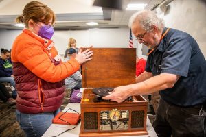 Clark Wood, right, starts repairs on a record player brought in to the Repair Cafe in November 2023 in Mountlake Terrace. (Olivia Vanni / The Herald)