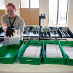 Simon Krane transfers ballots into boxes at the county elections center on Monday, Aug. 5, 2024 in Everett, Washington. (Olivia Vanni / The Herald)