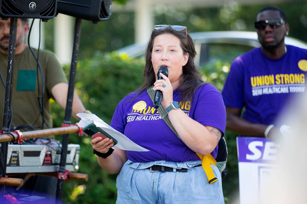 Clinician Chelsey Dyer speaks to a gathering of SEIU Healthcare 1199NW workers during a rally after picketing in front of the Compass Evaluation and Treatment building on Thursday, Aug. 1, 2024, in Mukilteo, Washington. (Ryan Berry / The Herald)