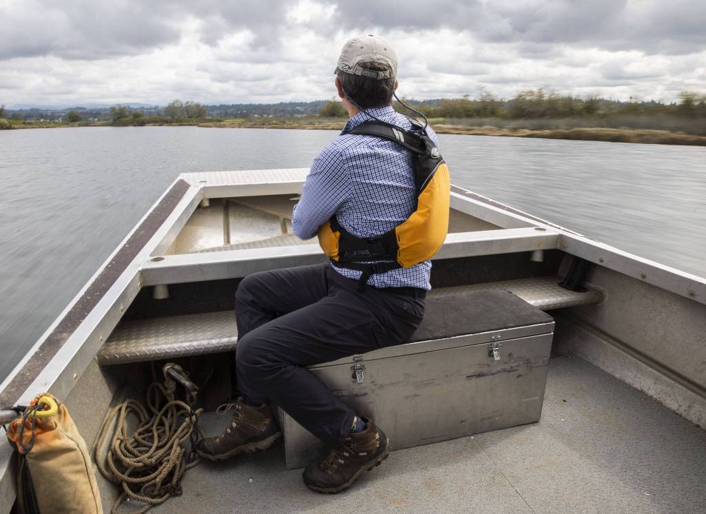 Erik Stockdale sits on the bow of a boat as it navigates through Union Slough on Tuesday in Snohomish. (Olivia Vanni / The Herald)