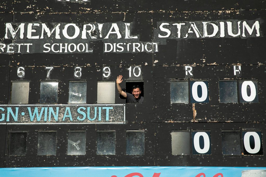 Herald sports reporter Nick Patterson waves from an opening in the Funko Field manual scoreboard on July 23, 2022, before an AquaSox game in Everett.