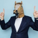 A man with a horse mask points up. (Getty Images)