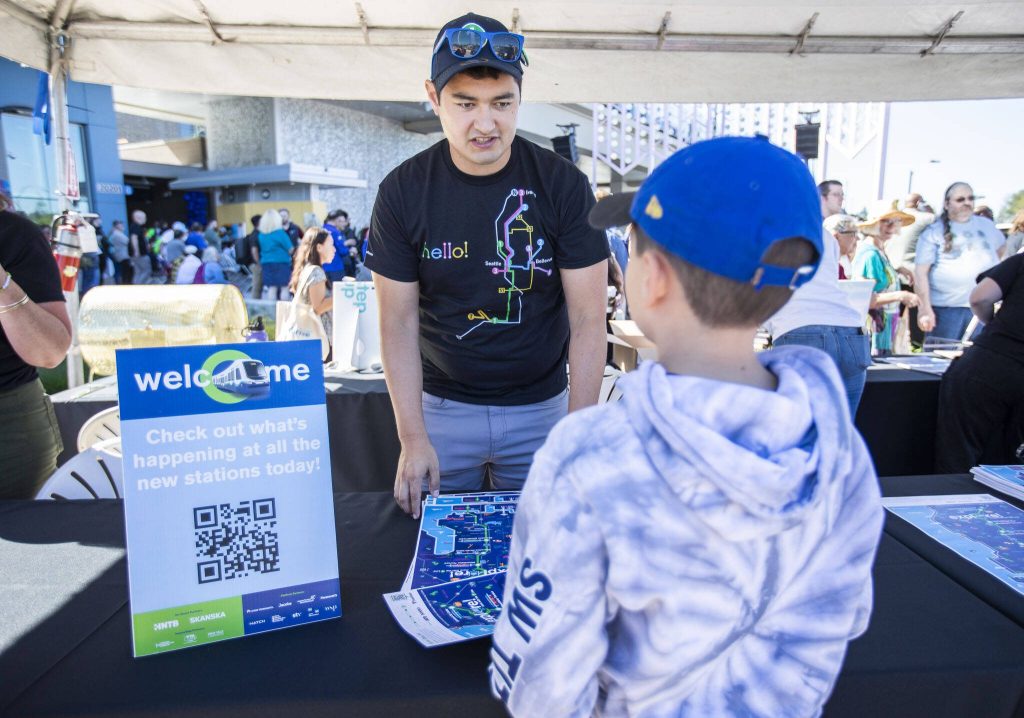 Sound transit employee Alex Ko hands out maps during the Lynnwood 1 Line extension opening celebrations on Friday, Aug. 30, 2024 in Lynnwood, Washington. (Olivia Vanni / The Herald)