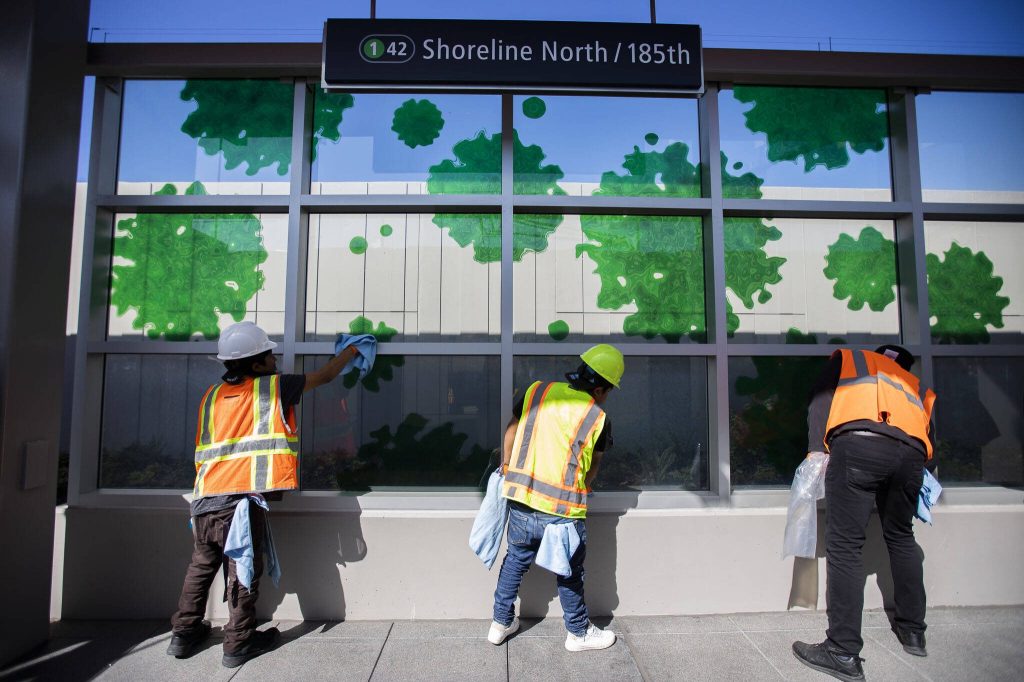 People clean the glass at the Shoreline North station on Wednesday, Aug. 28, 2024 in Shoreline, Washington. (Olivia Vanni / The Herald)