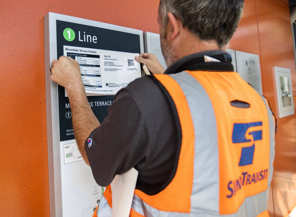 A Sound Transit employee places a fare and scheduling sheet at the Mountlake Terrace station on Wednesday, Aug. 28, 2024 in Mountlake Terrace, Washington. (Olivia Vanni / The Herald)