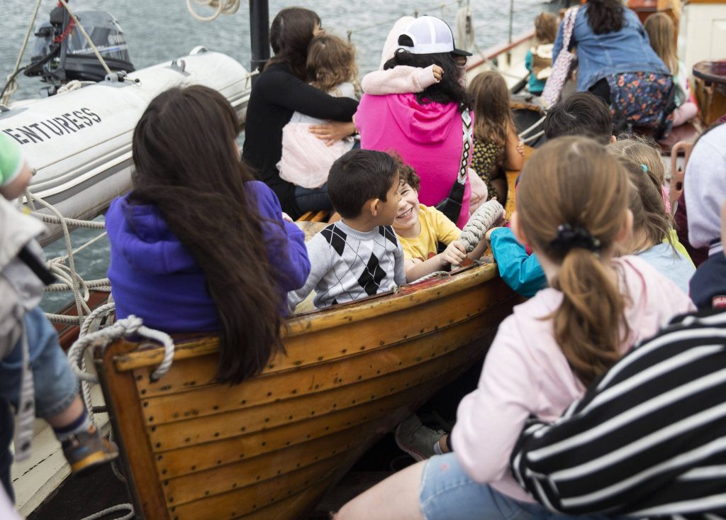 Kids sit in a lifeboat and listen to stories during the Everett Public Librarys Day Aboard the Adventuress on Tuesday, Aug. 27, 2024 in Everett, Washington. (Olivia Vanni / The Herald)