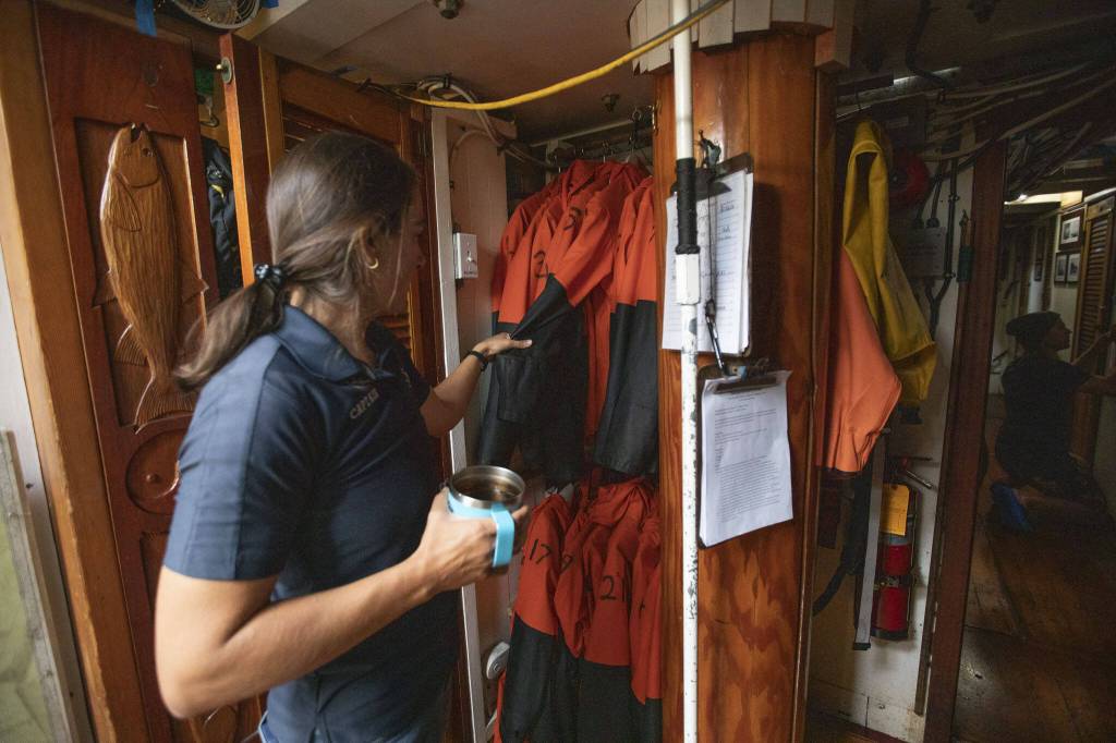 Captain Katelinn Shaw shows the rain gears students are assigned when they board the ship on Tuesday, Aug. 27, 2024 in Everett, Washington. (Olivia Vanni / The Herald)