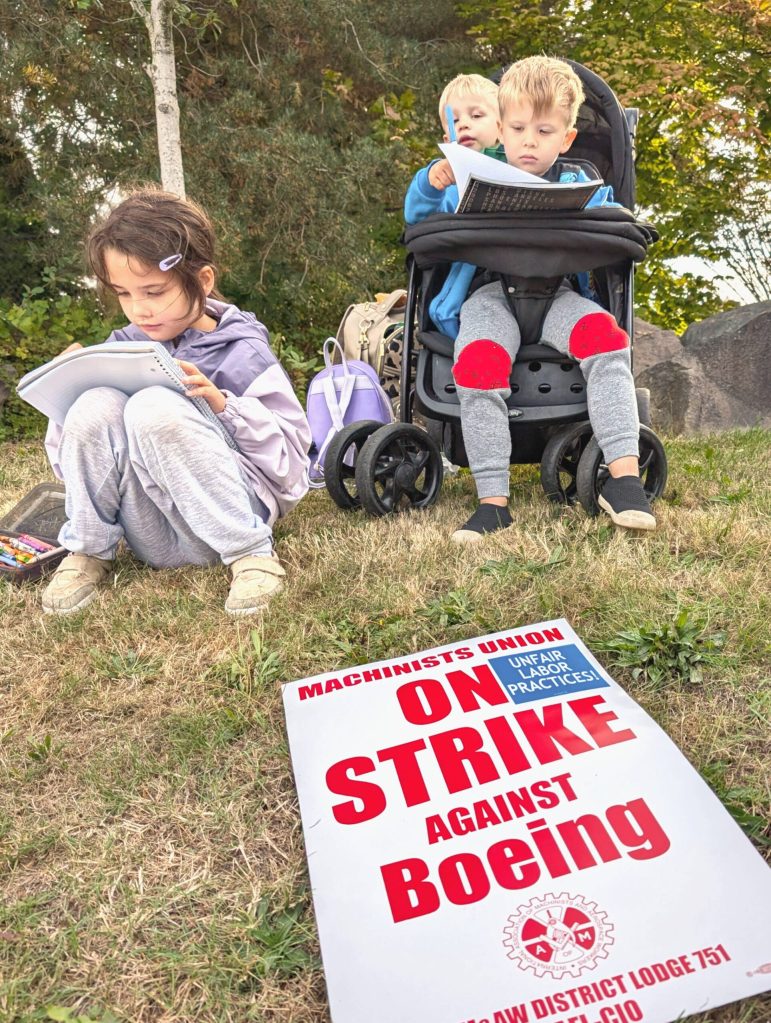 From left, Lana Redding,7, Bashy Redding, 2, and Theo Redding, 3, keep busy during a picket by the Boeing Machinists union at the Everett Boeing plant on Friday, Sept. 13, 2024, in Everett, Washington. (Michael Henneke / The Herald)
