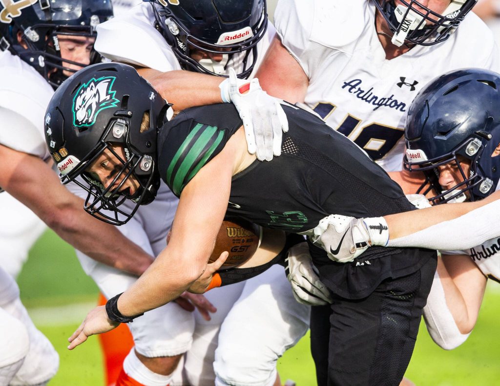 Jacksons Tyler Lykken is tackled by multiple Arlington players during the game on Friday, Sept. 20, 2024 in Everett, Washington. (Olivia Vanni / The Herald)