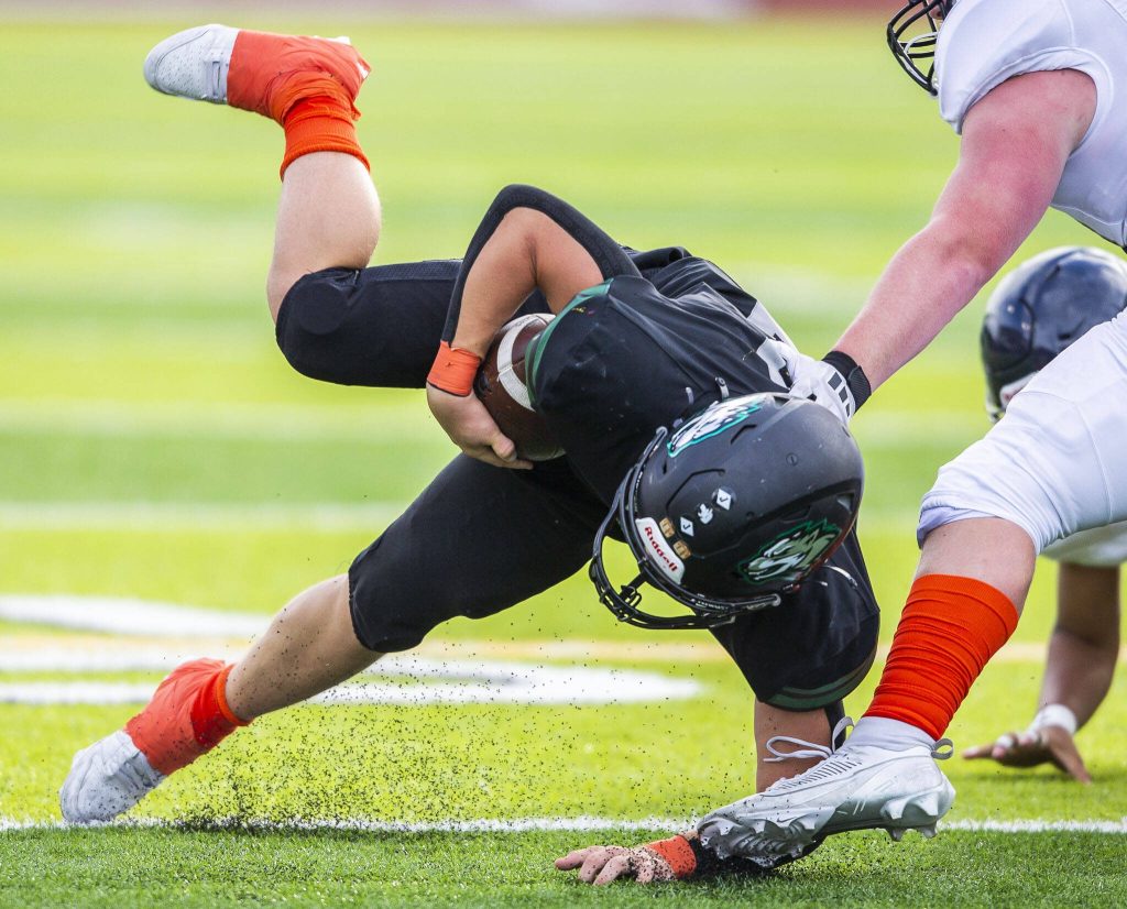 Jacksons Tyler Lykken gets triple dup while running the ball during the game against Arlington on Friday, Sept. 20, 2024 in Everett, Washington. (Olivia Vanni / The Herald)