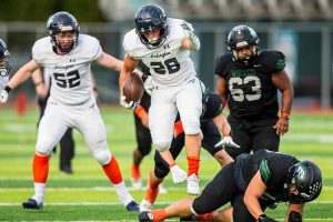 Arlington’s Caleb Reed leaps over a Jackson player while running the ball down the field during the game on Friday, Sept. 20, 2024 in Everett, Washington. (Olivia Vanni / The Herald)