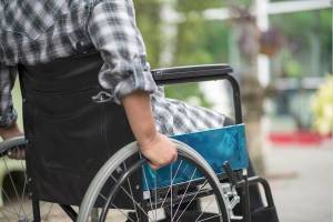 Close-up of senior woman hand on wheel of wheelchair during walk in hospital