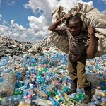 FILE - A man walks on a mountain of plastic bottles as he carries a sack of them to be sold for recycling after weighing them at the dump in the Dandora slum of Nairobi, Kenya on Dec. 5, 2018. The U.N. Environment Assembly (UNEA) unanimously voted Wednesday, March 2, 2022 in Nairobi, Kenya to start to create a legally binding global treaty to address plastic pollution in the world's oceans, rivers and landscape. (AP Photo/Ben Curtis, File)