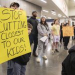 Grayson Huff, left, a 4th grader at Pinewood Elementary, peeks around his sign during the Marysville School District budget presentation on Tuesday, Nov. 28, 2023 in Marysville, Washington. (Olivia Vanni / The Herald)