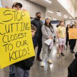Grayson Huff, left, a 4th grader at Pinewood Elementary, peeks around his sign during the Marysville School District budget presentation on Tuesday, Nov. 28, 2023 in Marysville, Washington. (Olivia Vanni / The Herald)