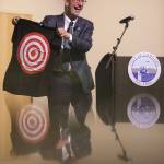 Edmonds Mayor Mike Rosen is reflected in a countertop as he pulls out a bullseye shirt at the start of his 2025 budget presentation at the Edmonds Waterfront Center on Tuesday, Oct. 1, 2024 in Edmonds, Washington. (Olivia Vanni / The Herald)