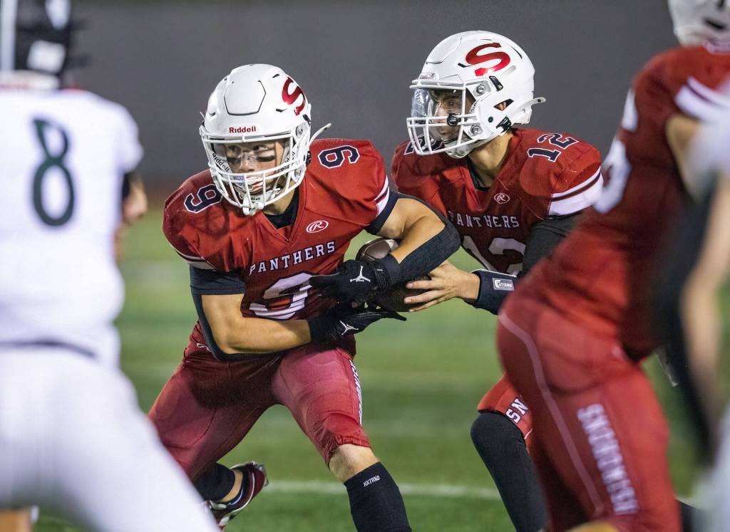 Snohomishs Evan Ruiz hands off the ball to Brody Strandt during the game against Mount Vernon on Friday, Oct. 4, 2024 in Snohomish, Washington. (Olivia Vanni / The Herald)