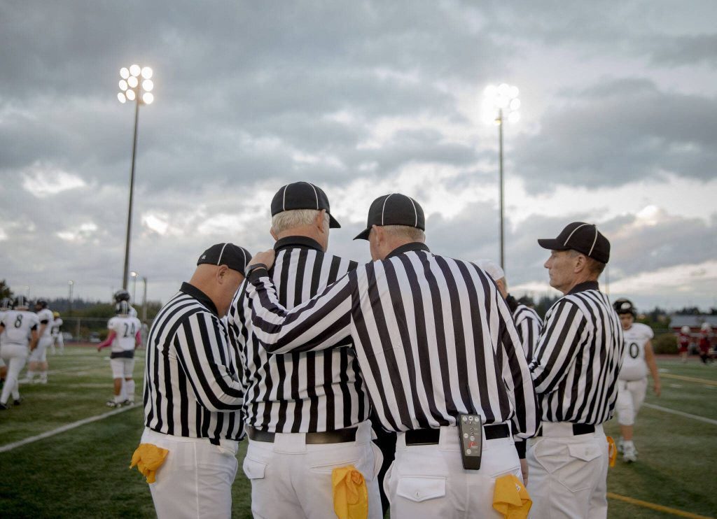 The officials gather to talk before the start of the football game on Friday, Oct. 4, 2024 in Snohomish, Washington. (Olivia Vanni / The Herald)
