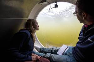 Bonnie Carl, left, and Josh Dean look out the dome as the OceanGate submarine Cyclops1 submerges in the Port of Everett Marina in 2017 in Everett. (Andy Bronson / The Herald)