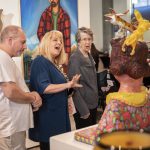 Megan Baron, center, reacts to an art piece by Cheri OBrien titled Eileen Tries to Remember If She Let the Dogs Out When She Left the House Five Hours Ago during the Schack Art Centers 50th Anniversary celebration on Thursday, Oct. 10, 2024 in Everett, Washington. (Olivia Vanni / The Herald)
