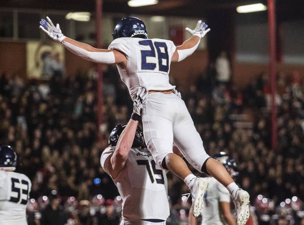 Arlingtons Dylan Scott lifts teammates Caleb Reed to celebrate Reeds touchdown during the Stilly Cup game against Arlington on Friday, Oct. 11, 2024 in Stanwood, Washington. (Olivia Vanni / The Herald)