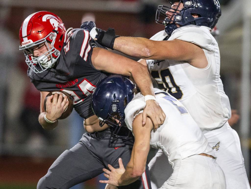 Stanwoods Cruise Swanson is tackled by Arlingtons Chase Deberry and Clay Heuer during the Stilly Cup game on Friday, Oct. 11, 2024 in Stanwood, Washington. (Olivia Vanni / The Herald)