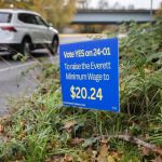 Cars getting onto an I-5 on-ramp drive past a sign encouraging people to vote YES on 24-01 to raise the Everett minimum wage on Tuesday, Oct. 29, 2024 in Everett, Washington. (Olivia Vanni / The Herald)