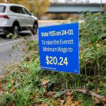 Cars getting onto an I-5 on-ramp drive past a sign encouraging people to vote “YES on 24-01” to raise the Everett minimum wage on Tuesday, Oct. 29, 2024 in Everett, Washington. (Olivia Vanni / The Herald)
